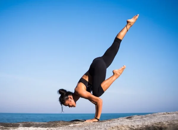 lady doing a yoga stretch on a rock by the water